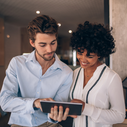 Image of man and woman in conversation, looking at a tablet together.