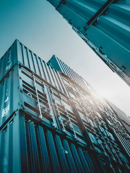 A stack of shipping containers against a blue sky, taken from ground perspective.